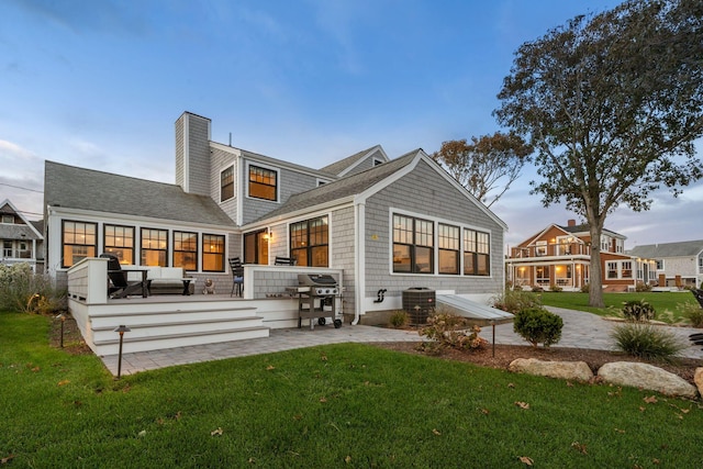 rear view of house featuring central AC, outdoor lounge area, a patio area, and a lawn