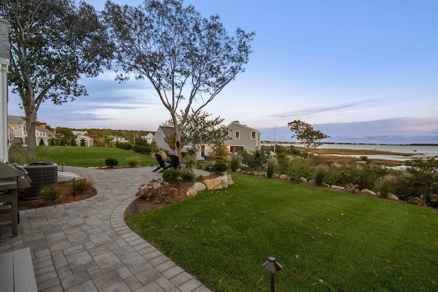 yard at dusk featuring a water view and central air condition unit