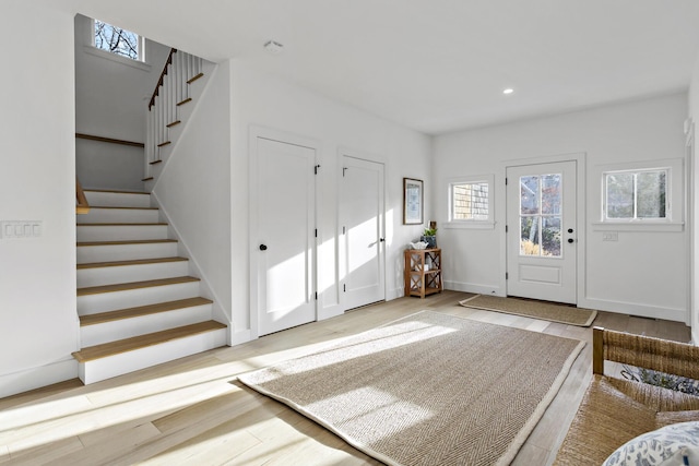 foyer entrance featuring recessed lighting, stairway, baseboards, and wood finished floors