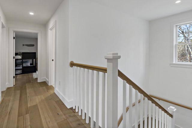 hallway with recessed lighting, an upstairs landing, baseboards, and light wood finished floors