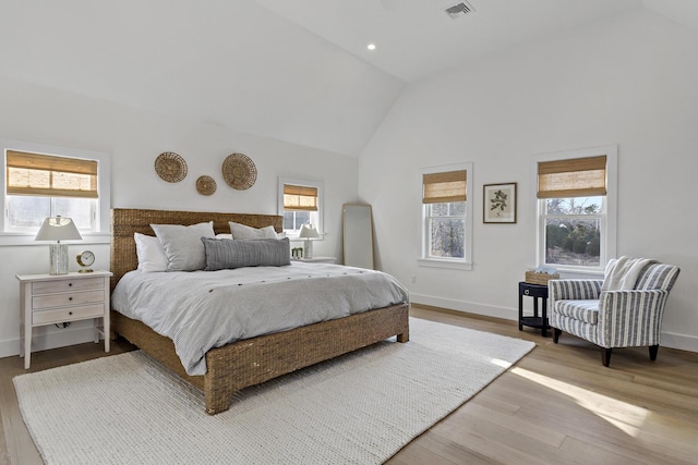 bedroom with high vaulted ceiling, hardwood / wood-style floors, and multiple windows