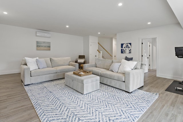 living area with baseboards, stairway, an AC wall unit, light wood-type flooring, and recessed lighting