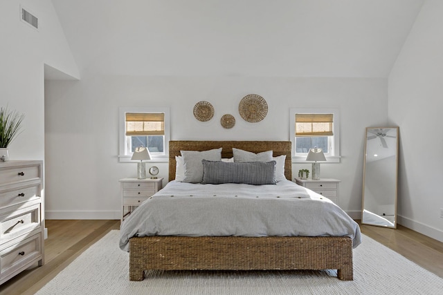 bedroom featuring multiple windows, lofted ceiling, and light hardwood / wood-style floors