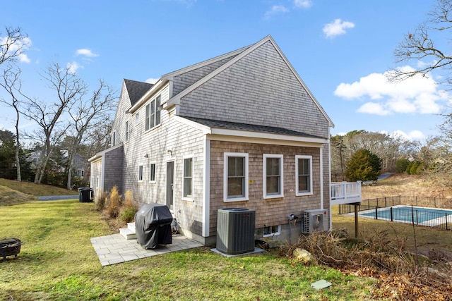 back of house with a fenced in pool, fence, central air condition unit, a patio area, and a lawn