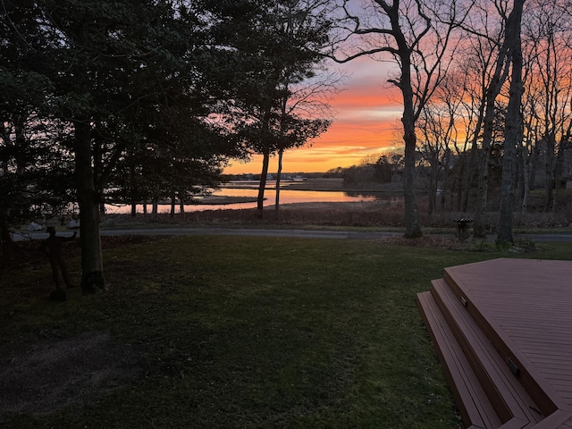 yard at dusk featuring a water view