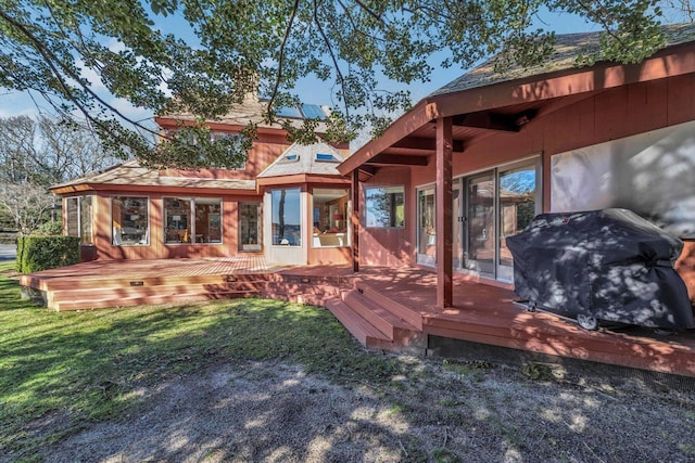 rear view of property with a deck and a lawn