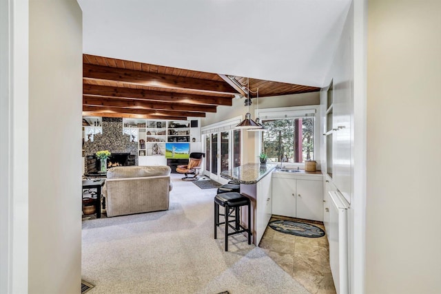 interior space featuring wood ceiling, white cabinetry, beamed ceiling, hanging light fixtures, and a breakfast bar area