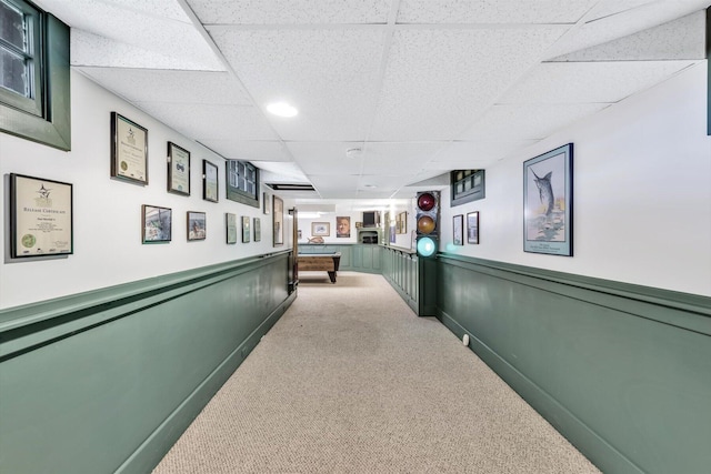 hall with light carpet and a drop ceiling