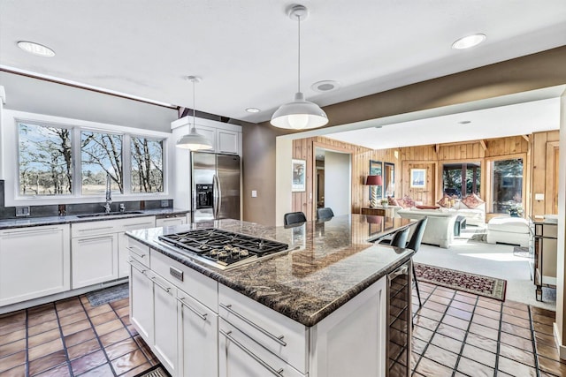 kitchen featuring decorative light fixtures, white cabinetry, stainless steel appliances, dark stone counters, and wood walls