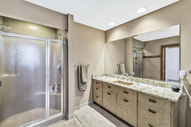 bathroom featuring a shower with door and vanity