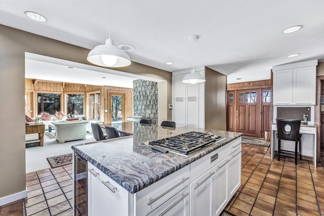 kitchen featuring a kitchen breakfast bar, white cabinets, stainless steel gas stovetop, and a center island