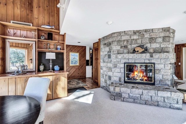 carpeted living room with a brick fireplace and wood walls