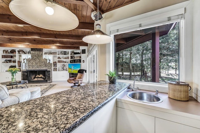 kitchen featuring white cabinets, wood ceiling, built in shelves, a fireplace, and sink