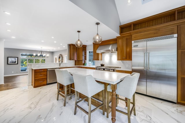 38 Beach Plum Hill Rd, Osterville, MA 02655 - kitchen with stainless steel appliances, a peninsula, wall chimney range hood, light countertops, and brown cabinets
