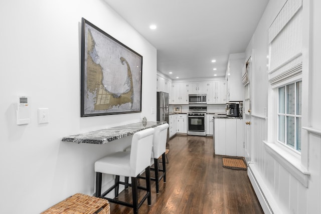 193 Main St, Sandwich, MA 02563 - kitchen with dark wood-style flooring, a peninsula, white cabinetry, appliances with stainless steel finishes, and a baseboard radiator