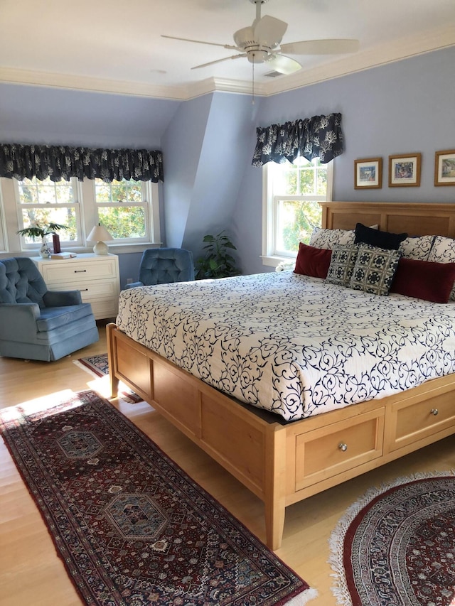 bedroom with light hardwood / wood-style floors, ceiling fan, ornamental molding, and vaulted ceiling