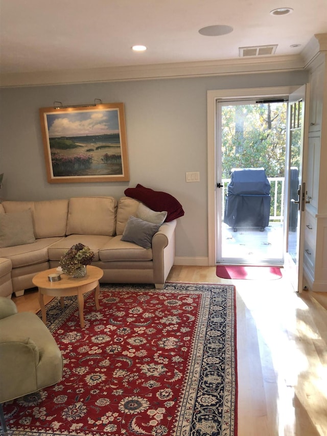 living room with wood-type flooring and ornamental molding