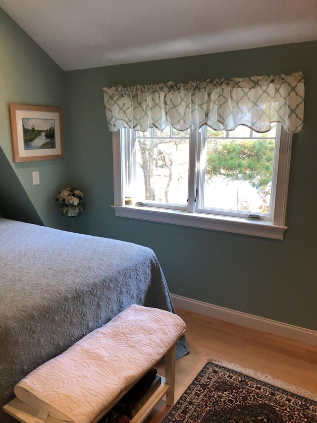 bedroom with wood-type flooring, multiple windows, and lofted ceiling