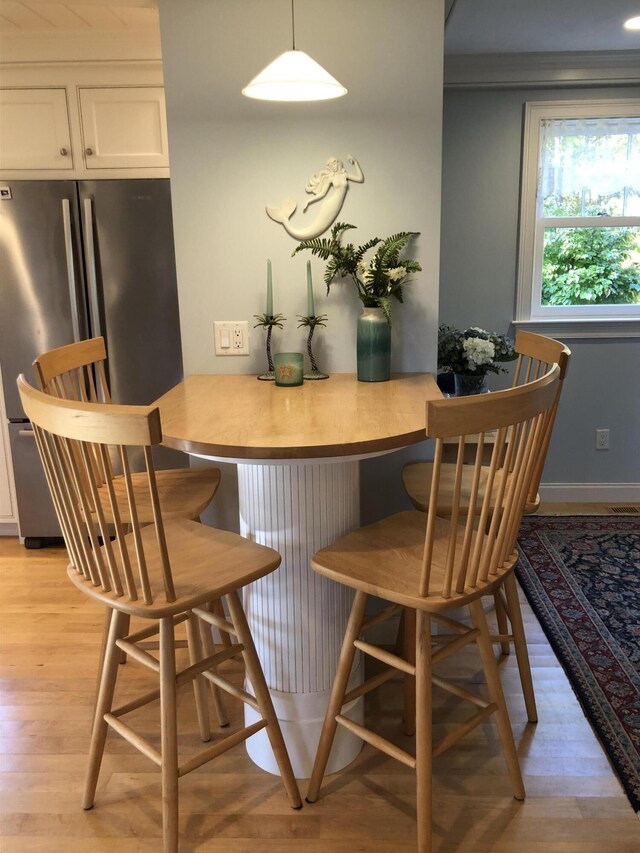 interior space with white cabinetry, pendant lighting, light hardwood / wood-style flooring, and stainless steel refrigerator