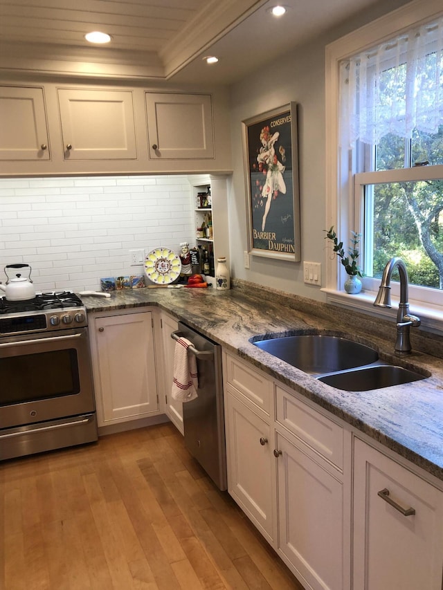 kitchen featuring backsplash, sink, white cabinets, and appliances with stainless steel finishes