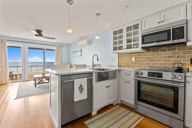 kitchen with pendant lighting, white cabinetry, stainless steel appliances, kitchen peninsula, and a water view