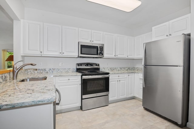 12 Wildflower Vlg, Yarmouth Port, MA 02675 - kitchen featuring stainless steel appliances, a sink, white cabinets, and light stone countertops