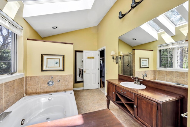 bathroom featuring vaulted ceiling with skylight, a shower stall, a tub with jets, tile patterned floors, and vanity