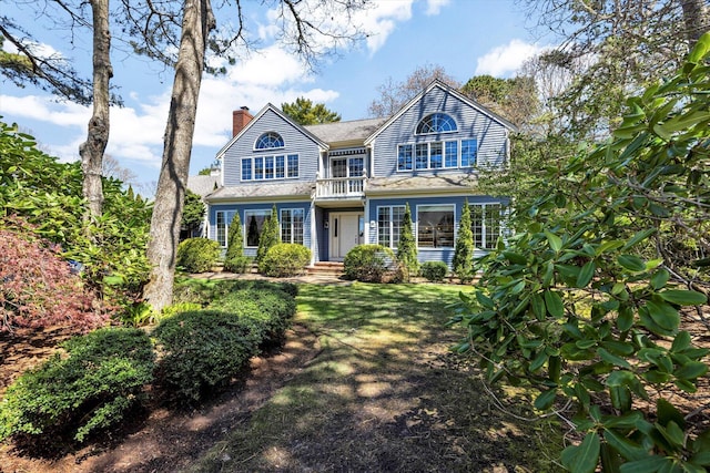 view of front of property with a shingled roof, a balcony, and a chimney