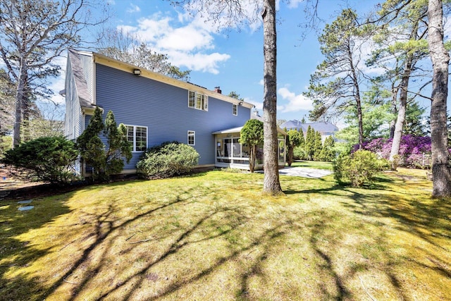 rear view of house featuring a lawn, a chimney, and a sunroom
