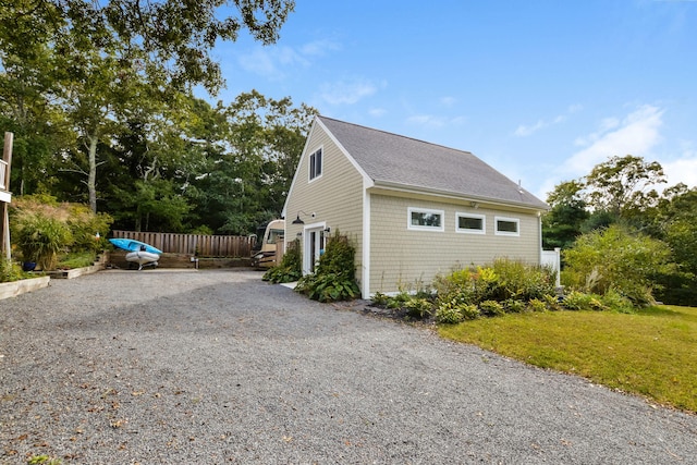10 Westerly Dr, Bourne, MA 02532 - view of side of property with a lawn, gravel driveway, fence, and a shingled roof