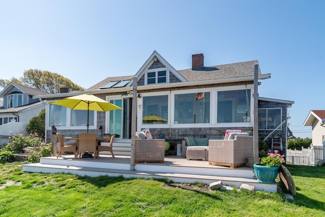 back of property with a chimney, a sunroom, a patio, and a shingled roof