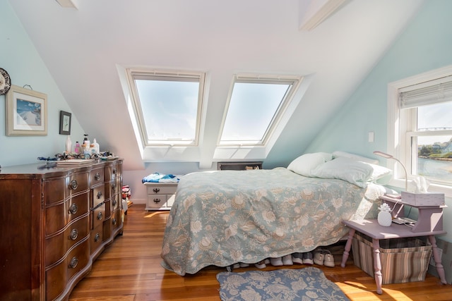bedroom with lofted ceiling, a skylight, and wood finished floors