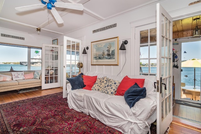 living area with french doors, hardwood / wood-style flooring, healthy amount of natural light, and crown molding
