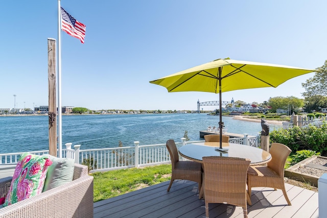 wooden terrace with a water view and outdoor dining space