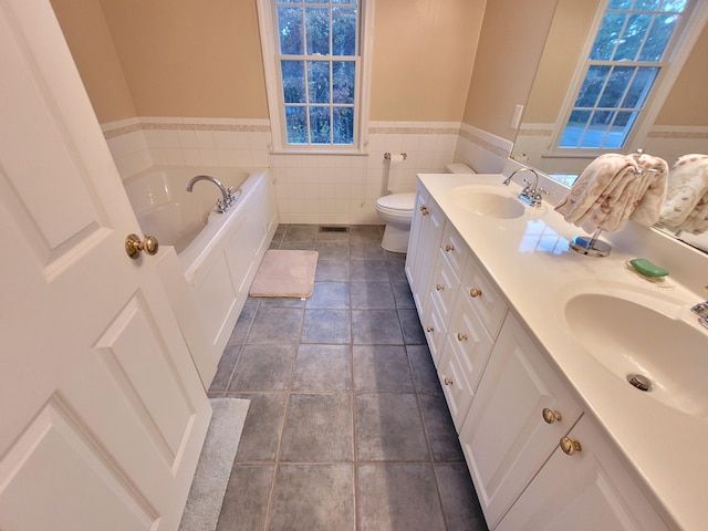 bathroom featuring tile patterned floors, a tub to relax in, toilet, tile walls, and vanity