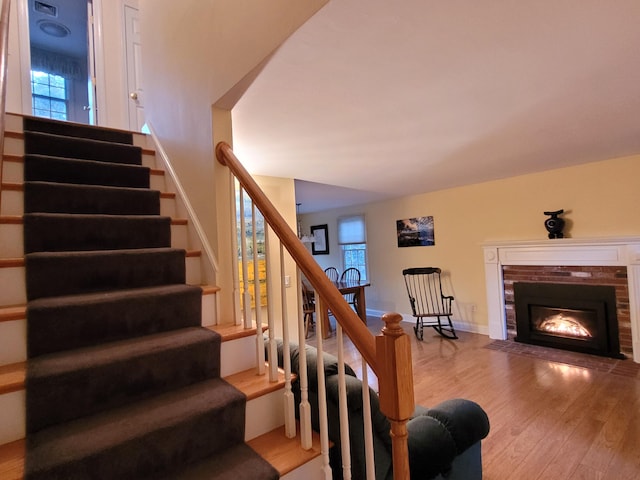 stairway featuring wood-type flooring and a fireplace