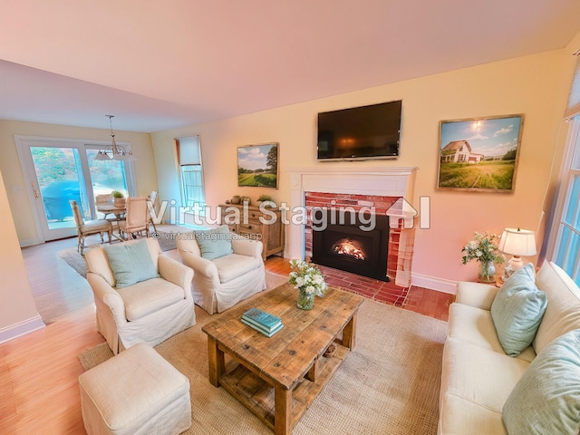 living room featuring an inviting chandelier, a fireplace, and light hardwood / wood-style floors