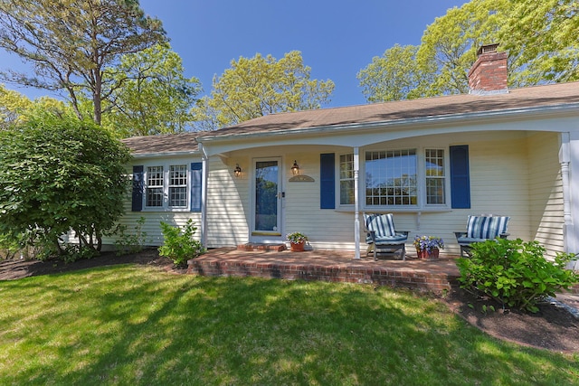54 Mcnamara Ave, West Yarmouth, MA 02673 - view of front of property featuring a front lawn, a chimney, and covered porch