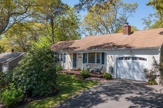 54 Mcnamara Ave, West Yarmouth, MA 02673 - view of front facade with a garage, asphalt driveway, a chimney, and a shingled roof