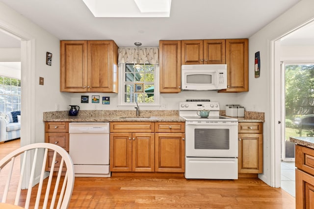 54 Mcnamara Ave, West Yarmouth, MA 02673 - kitchen with white appliances, a sink, light wood-style floors, a skylight, and brown cabinetry