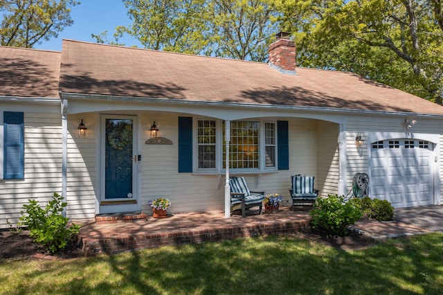 54 Mcnamara Ave, West Yarmouth, MA 02673 - doorway to property featuring a garage, a chimney, roof with shingles, and a porch