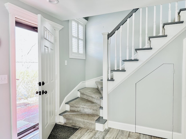 entryway with stairway, wood finished floors, and baseboards