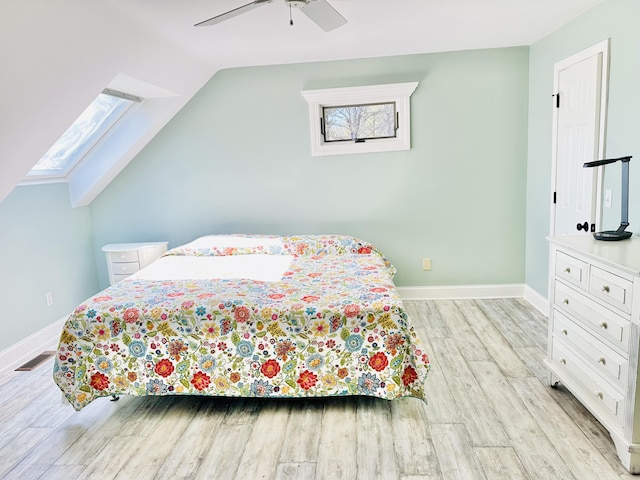 bedroom featuring vaulted ceiling with skylight, multiple windows, light wood-style floors, and visible vents