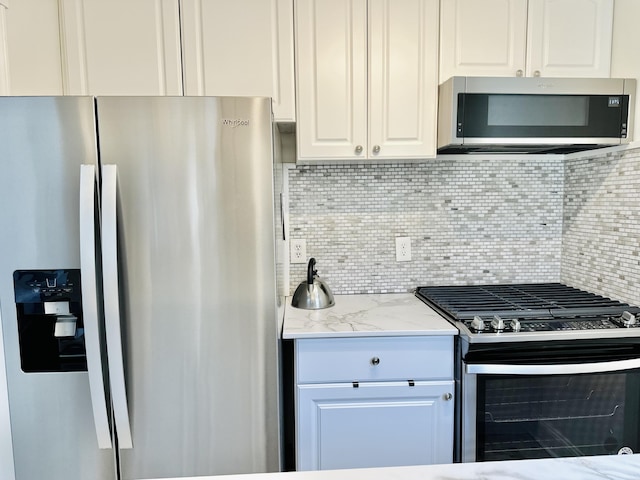 kitchen featuring light stone counters, stainless steel appliances, tasteful backsplash, and white cabinetry