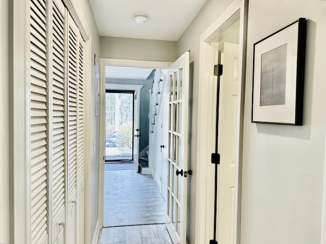 hall with french doors, baseboards, and wood finished floors