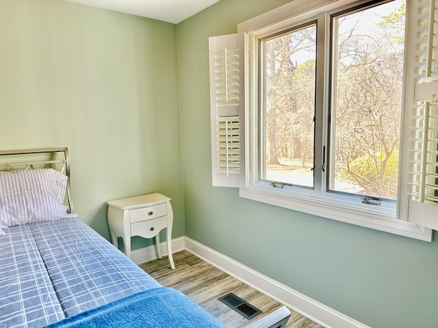 bedroom with visible vents, multiple windows, baseboards, and wood finished floors