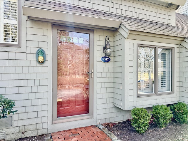 view of exterior entry with a shingled roof