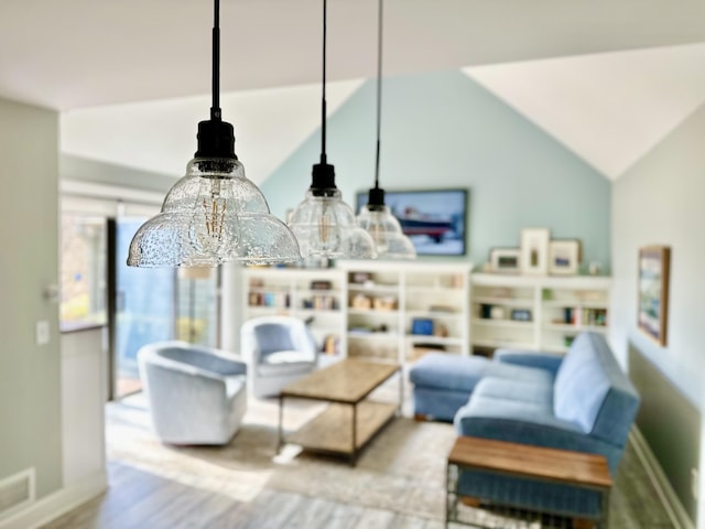 living room with visible vents, wood finished floors, baseboards, an inviting chandelier, and lofted ceiling