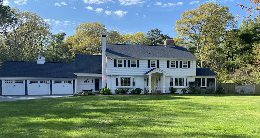 211 Pleasant St, South Yarmouth, MA 02664 - colonial-style house featuring a garage, concrete driveway, a chimney, and view of scattered trees