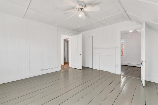 unfurnished room with a baseboard heating unit, dark wood-style flooring, lofted ceiling, and a ceiling fan